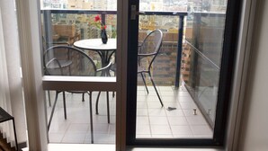 Ein Balkon mit Tisch und Stühlen, einer Blumenvase und Blick auf die Stadt.