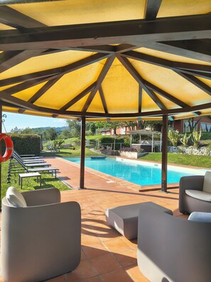 A covered outdoor area with a pool, lounge chairs, and a lifebuoy.
