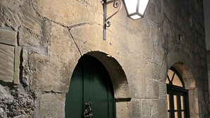 A stone building with a green door and a lantern above it.