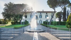 Ein Gebäude mit einem zentralen Brunnen, umgeben von einem Kiesweg und Metallgeländern.