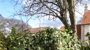 A wooden bench in a garden with a stone wall and a tree. - Spacious House 3 ensuite bedrooms, sleeps 6, Centre of Helmsley, Pet friendly,  (Helmsley)