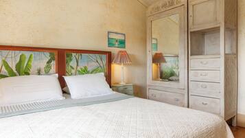 A bedroom with a bed, two bedside tables, a dresser with drawers, a mirror, and a painting on the wall.