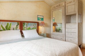 Een slaapkamer met een bed, twee nachtkastjes, een dressoir met lades, een spiegel en een schilderij aan de muur.