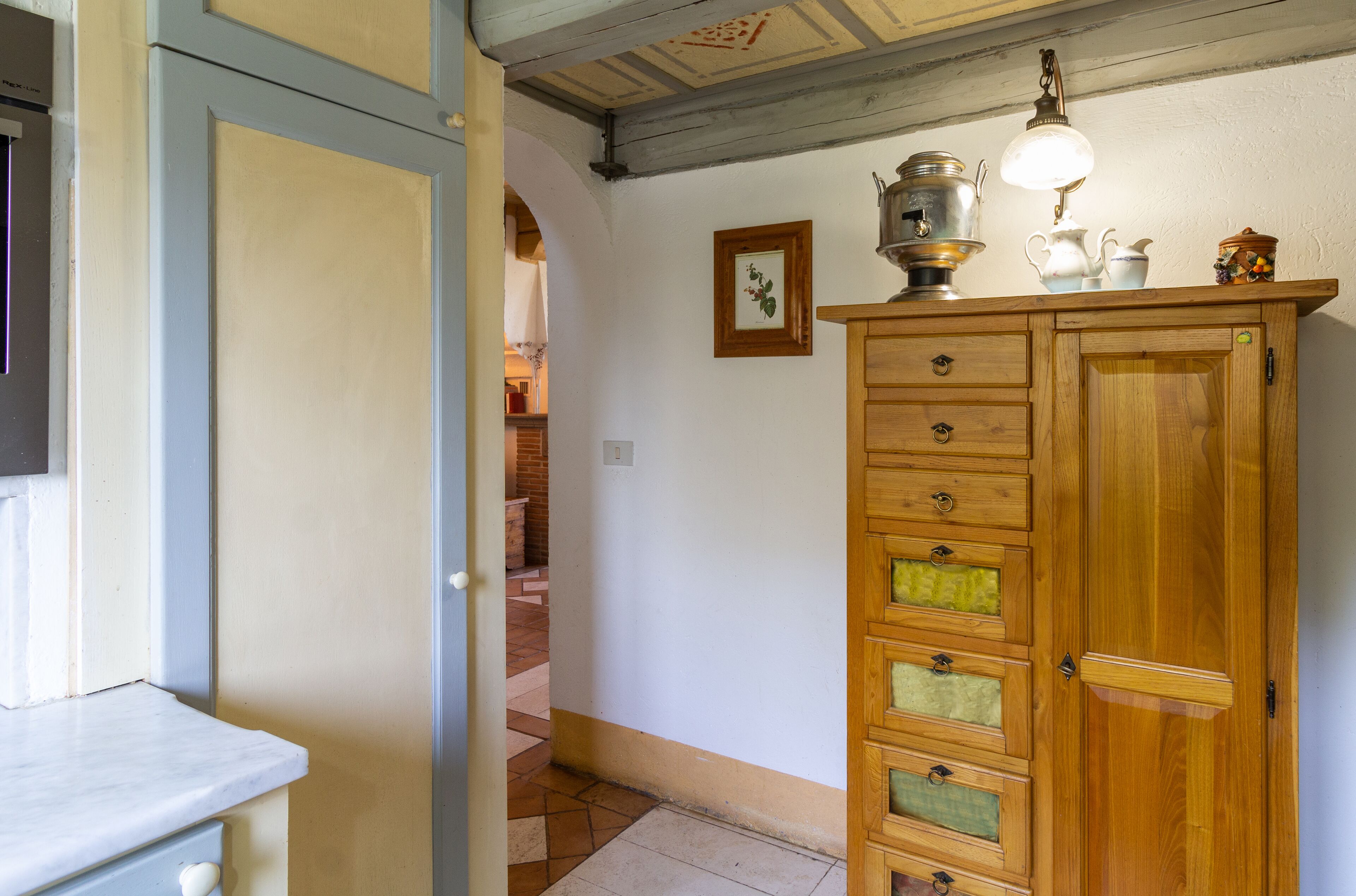 A wooden cabinet with multiple drawers and a hanging light fixture.