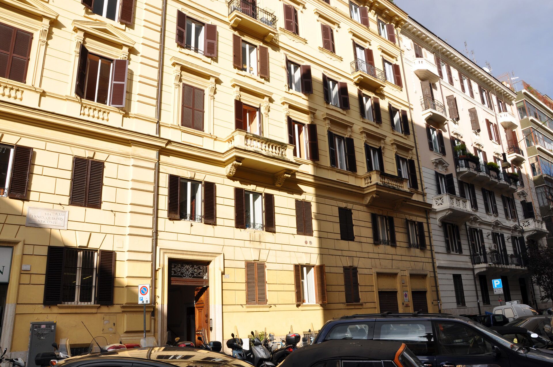 Un immeuble à plusieurs étages, doté d’une façade jaune, de nombreux balcons et d’un panneau indiquant un espace de stationnement.