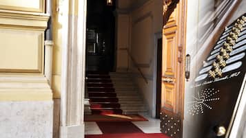 A grand staircase with a red carpet leading to a wooden door with brass handles.