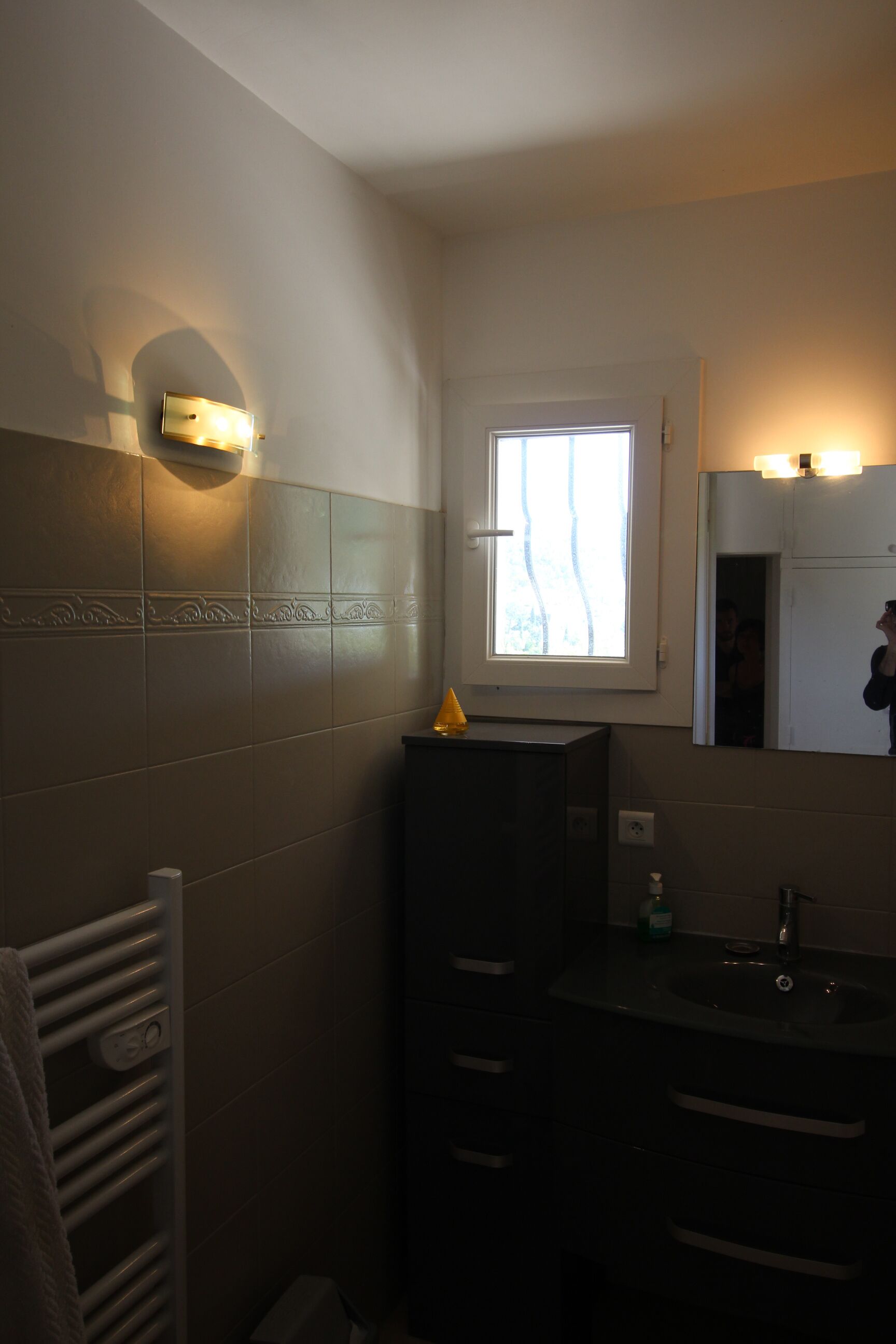 Ein Badezimmer mit Fenster, Handtuchhalter, Waschbecken und Spiegel.