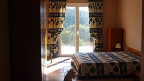 A bedroom with a bed, a nightstand, a lamp, and a window with curtains.