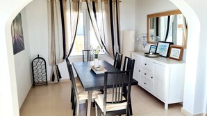 A dining area with a dark wooden table, black chairs, and a white cabinet with framed pictures. - Beautiful villa private pool stunning Panoramic Sea & Mountain Views in Moraira, (Moraira)