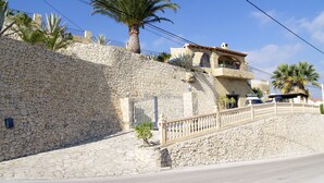 A stone-walled building with a balcony, a palm tree, and a clear blue sky. - Beautiful villa private pool stunning Panoramic Sea & Mountain Views in Moraira, (Moraira)
