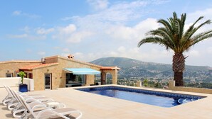 A rooftop pool with lounge chairs, a palm tree, and a mountain view. - Beautiful villa private pool stunning Panoramic Sea & Mountain Views in Moraira, (Moraira)