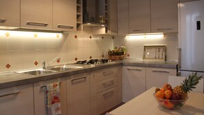 A modern kitchen with stainless steel appliances, wooden cabinets, and a fruit bowl on the counter. - 80m², Todo Reformado, Fibra Wifi, Estação Central, Metrô a Poucos Minutos (Milano)