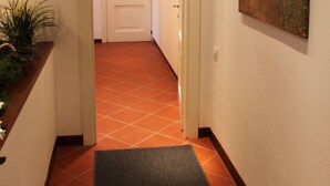 A hallway with a tiled floor, a door at the end, and a painting on the wall. - 80m², Todo Reformado, Fibra Wifi, Estação Central, Metrô a Poucos Minutos (Milano)
