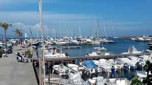 A marina with numerous boats docked, a pedestrian walkway, and palm trees. - New villa 2 levels located in a quiet residence and close to services (San Felice Circeo)