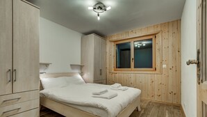 A bedroom with a wooden bed, a wardrobe, and a window. - Appartement Matins St Laurent 1b - La Tzoumaz, 4 Vallees (La Tzoumaz)
