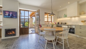 A modern kitchen with white cabinetry, a central island, and a dining area with white chairs. - Casa Son Bordoi, private pool & tranquility (Llubí)