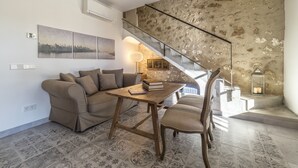 A living room with a sofa, a wooden table, and a chair. There is a staircase with a stone wall and a railing. - Casa Son Bordoi, private pool & tranquility (Llubí)