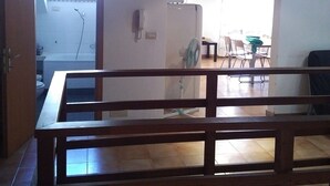 An open-plan living and dining area with a wooden dining table, chairs, a kitchen area with a refrigerator, and a window providing natural light. - Castello apartment with terrace (Venezia)