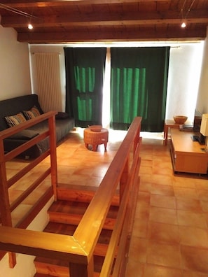 A wooden staircase leading to a living area with a sofa, a small table, and a bowl on a stool.