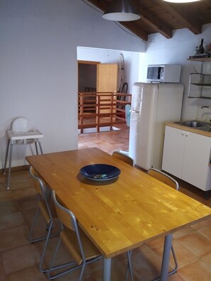 A compact kitchen with a wooden dining table, a microwave, and a refrigerator.