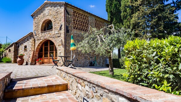 Un edificio de piedra con una gran entrada en arco, escalones que conducen a la entrada y un asta con una bandera.