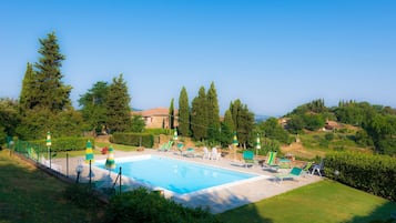 Relax by the serene pool surrounded by lush greenery and tall trees.