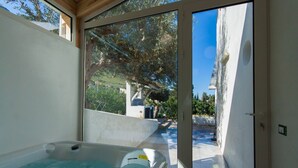 A spa area with a hot tub and a glass door leading to a pool. -  Villa antico pozzo: pool, spa, sauna, sea view, 15 minutes from Scopello (Castellammare del Golfo)
