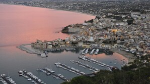 A coastal town with a marina filled with boats, historic buildings, and a prominent castle-like structure. -  Villa antico pozzo: pool, spa, sauna, sea view, 15 minutes from Scopello (Castellammare del Golfo)