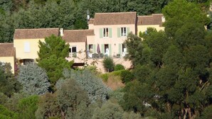 Un groupe de maisons aux toits de tuiles, entourées d’une forêt dense.