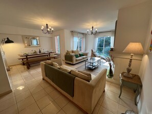 Un salon spacieux comprenant un canapé, une table basse et un coin repas avec une banquette.