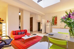 A modern living room with a red sofa, a small coffee table, and a dining area with a table and chairs. - Selci | 10-minutes walk from the Colosseum! (Roma)