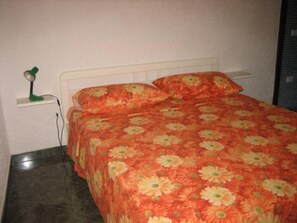 A bed with a floral bedspread, a nightstand with a lamp, and a white headboard. - House / Villa - Marsala (Marsala)