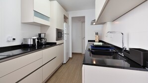 A modern kitchen with white cabinets, a black countertop, a built-in oven, a microwave, and a coffee maker. - Flat in Benidorm Renovated Frontline with Terrace (Benidorm)