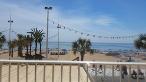 A beach with palm trees, blue lounge chairs, and a wooden deck. - Flat in Benidorm Renovated Frontline with Terrace (Benidorm)