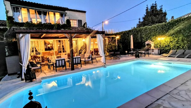 Piscina com área coberta, espaço para sentar ao ar livre e vista para um edifício com terraço.
