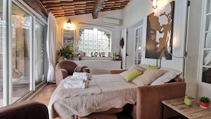 Um quarto aconchegante com uma cama, uma cadeira, uma mesa e uma janela com vista.