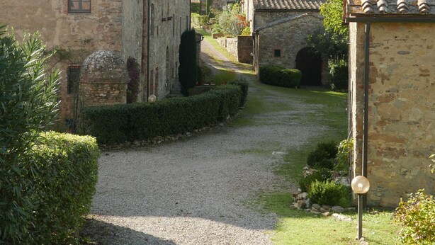 Un bâtiment en pierre avec un chemin de gravier menant à un portail.