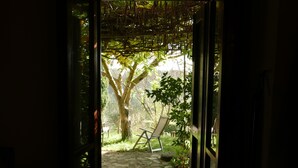 Un chemin de pierres mène à un espace extérieur aménagé avec des sièges, sur lequel se trouve une pergola.