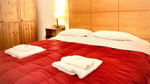 A hotel room with a red bedspread, white pillows, and a wooden headboard.