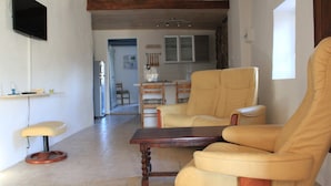 Un salon avec un canapé, une table basse en bois et un téléviseur fixé au mur.