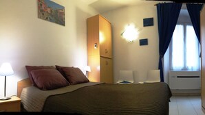 A hotel room with a bed, bedside lamps, a wardrobe, a mirror, and a window with curtains. - Apartment/ flat - Bonifacio (Bonifacio)