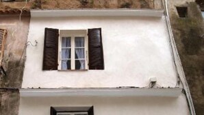 A two-story building with a white facade, a balcony with a glass railing, and a door with a circular emblem. - Apartment/ flat - Bonifacio (Bonifacio)