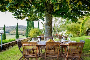 An outdoor dining area with a wooden table and chairs, surrounded by greenery and a view of the countryside. - ALL PROPERTY 7BR- Charming Tuscan Villa with pool, hot tub, A/C,Siena 15 km (Siena, Toscana)