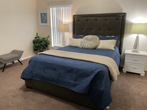 A bedroom with a large bed, a nightstand, a chair, and a potted plant. - 15 min from Disney, private pool in secure gated community (Davenport)