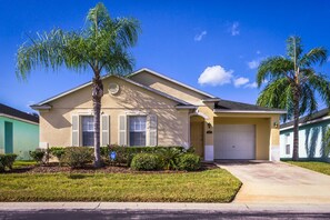A single-story house with a beige exterior, a front garage, and a well-maintained lawn. - 15 min from Disney, private pool in secure gated community (Davenport)