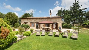 Una casa de piedra con patio, mobiliario exterior y jardín.