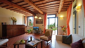 Una sala de estar acogedora con techo de madera, un sofá, un sillón y un televisor.