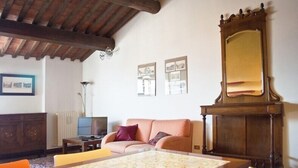 Un salon avec un plafond en bois, un grand miroir, un canapé, un téléviseur et des tableaux encadrés accrochés au mur.