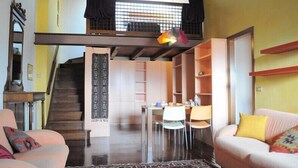Un vaste espace de vie doté d’un haut plafond, d’un escalier et d’un coin repas.