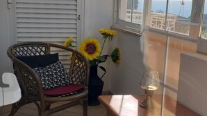 A room with wicker furniture, a window with blinds, and a view of the sea. - Villa with private pool, terrace and sea views (Albufeira)